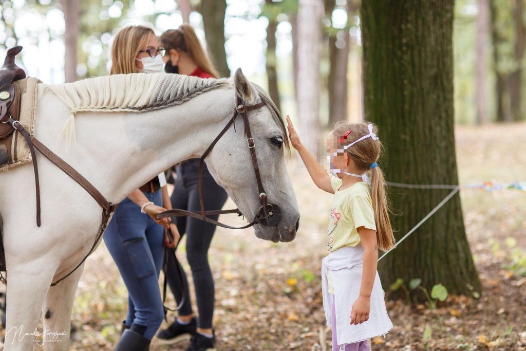 Devojčica mazi konja.